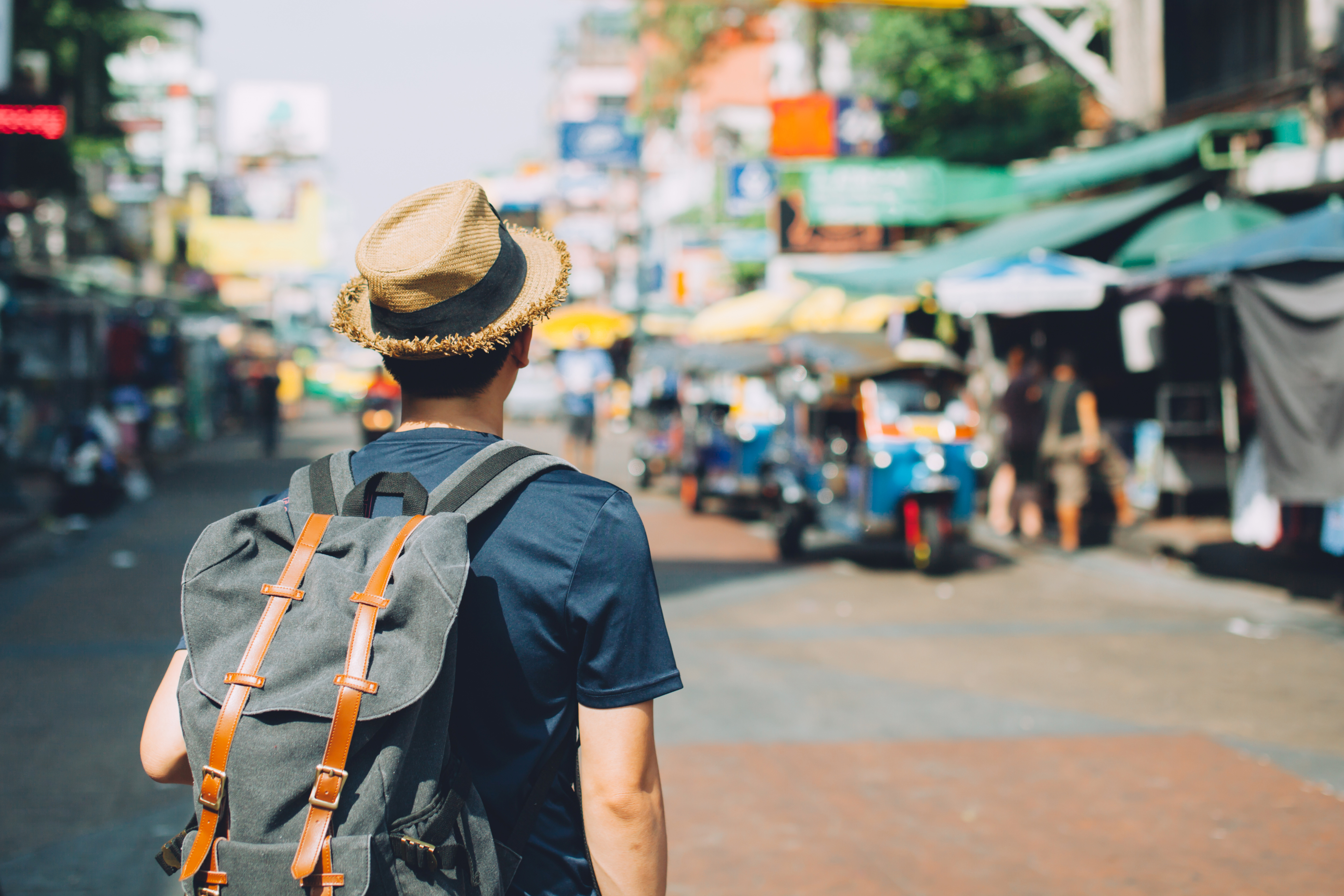 expat tax services A man with a backpack walking through a busy street marketplace