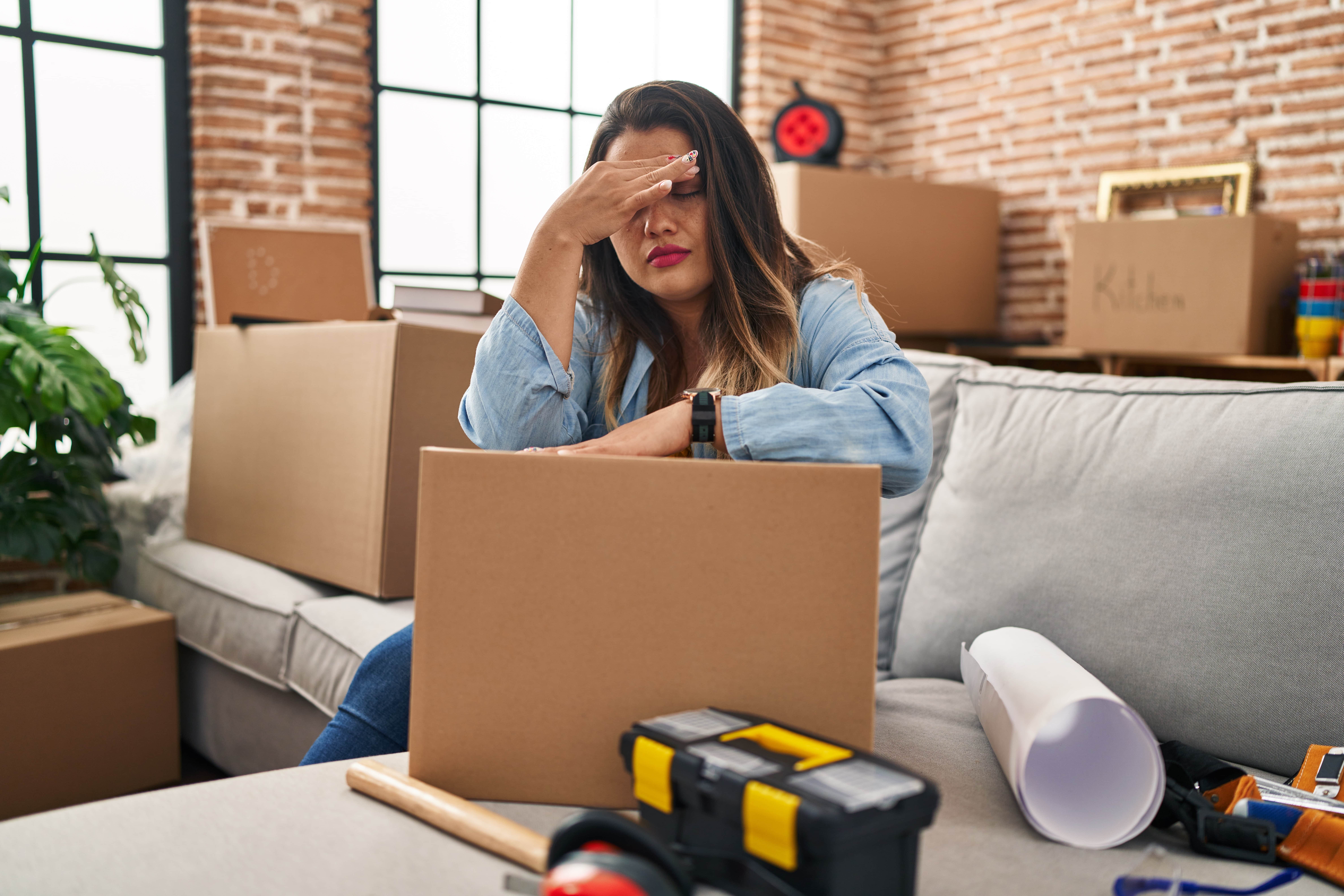 Stressed woman packing for a move Young plus-size woman sitting on floor surrounded by moving boxes, looking stressed while packing for a move